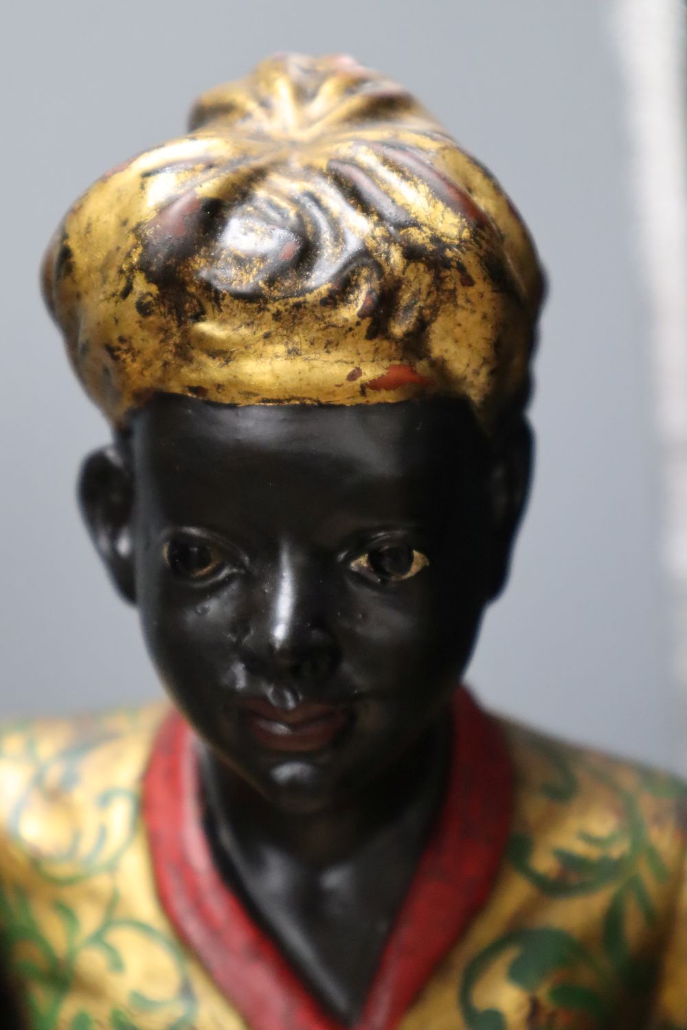 A pair of gilt and polychrome painted Nubian butlers, portrayed holding shell shaped trays